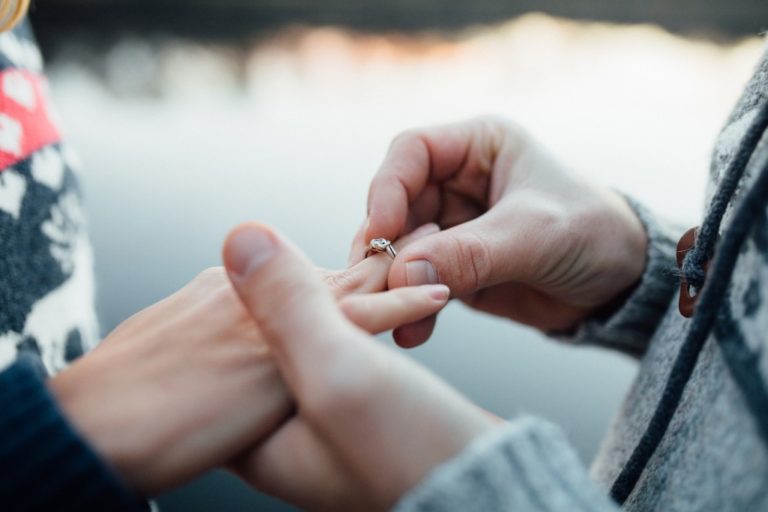 Man putting an engagement ring on woman's hand