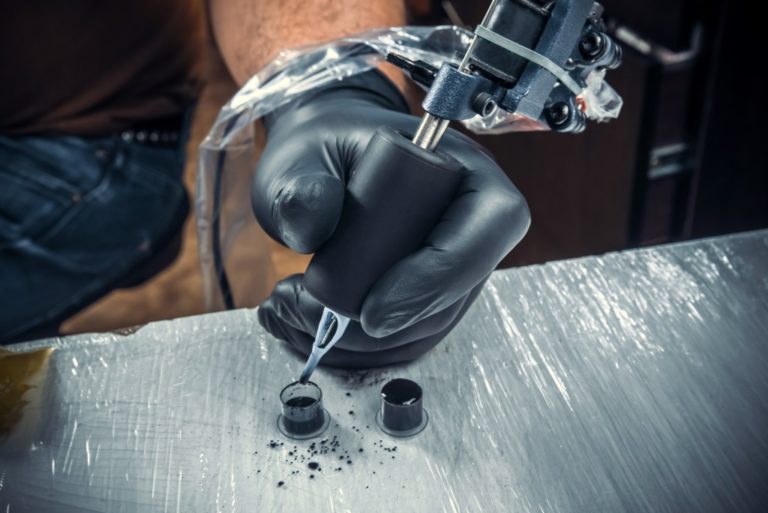 Man dipping ink to the tattoo gun