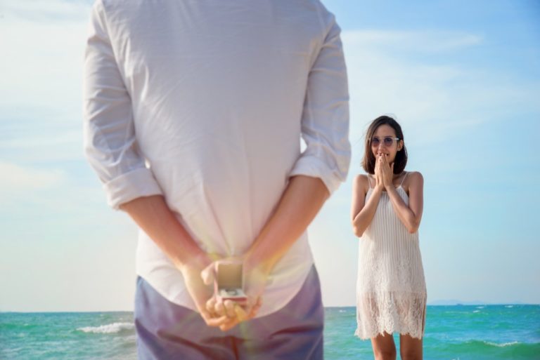 Man hiding engagement ring behind him before asking the woman to marry him