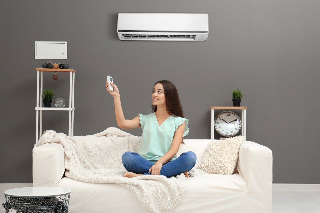 woman turning the airconditoner on in the living room