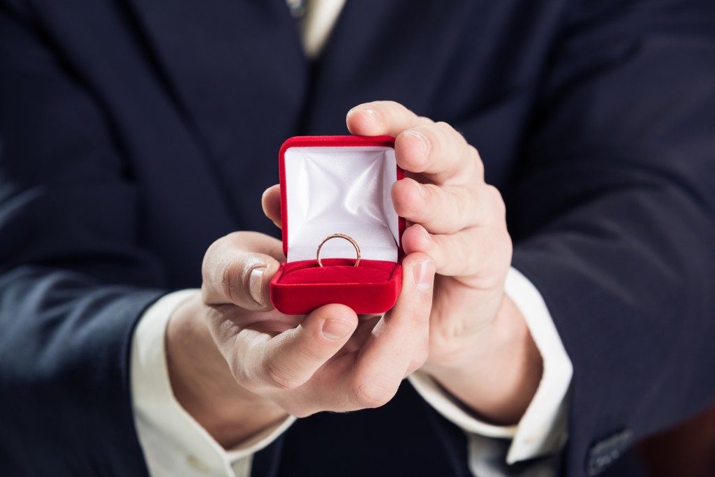 Close up of man holding wedding ring and gift box