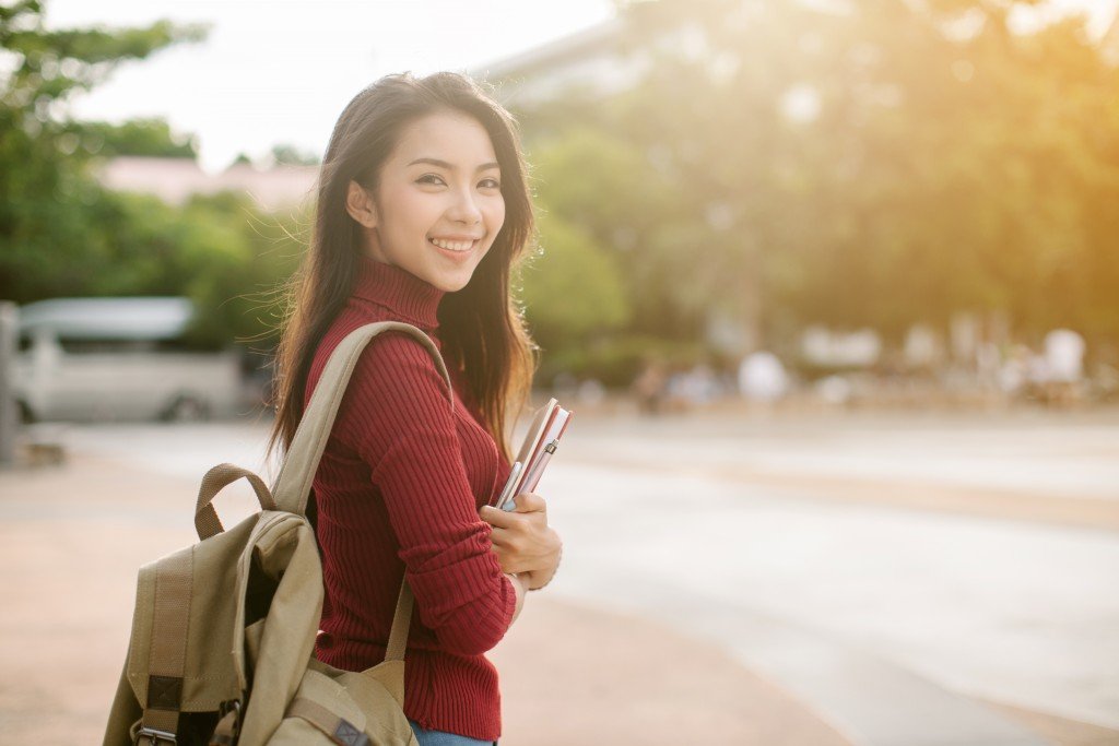 Asian female with backpack and notebooks