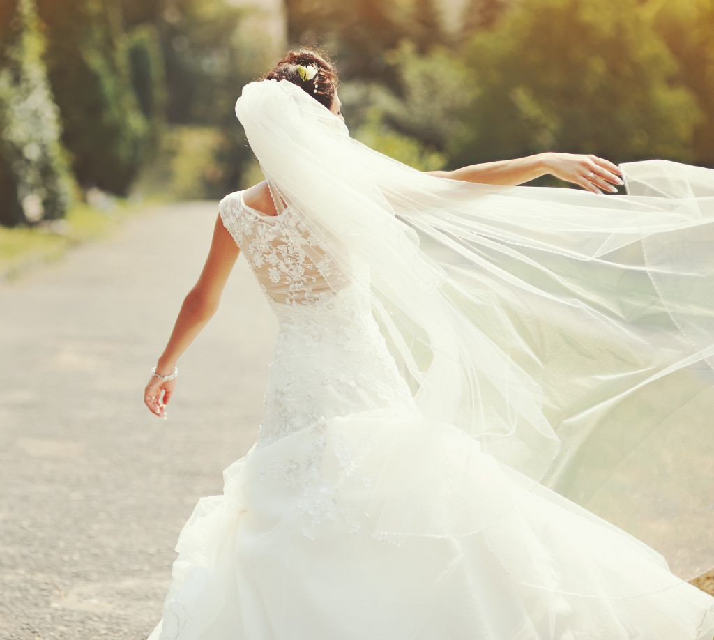 Bride in wedding dress and veil spinning outdoors
