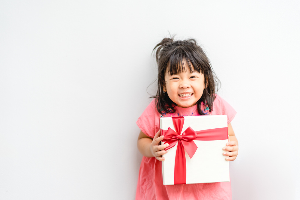 little girl smiling while holding a gift