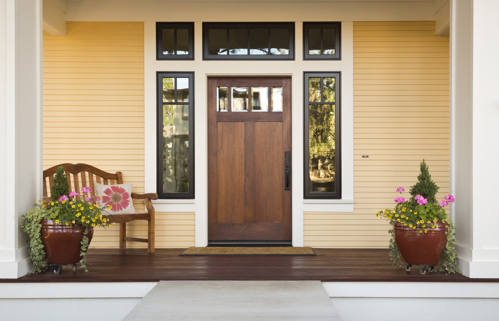front door of a house with seating and neutral colors and plants