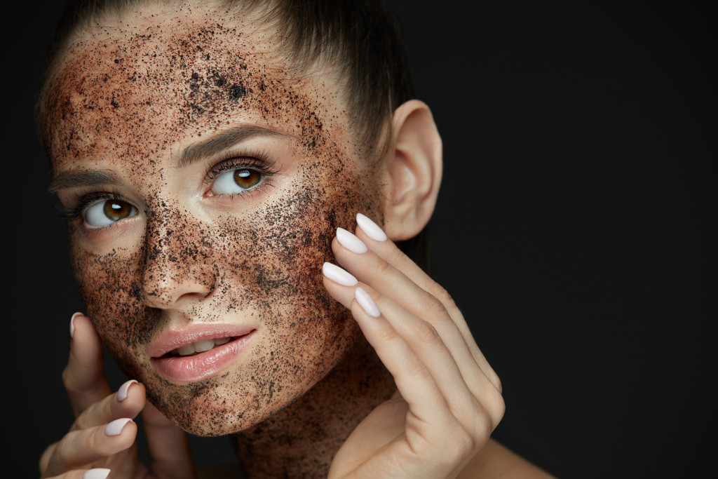 woman with exfoliating scrub in her face and black background