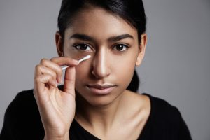 young woman with a cotton stick correcting a makeup