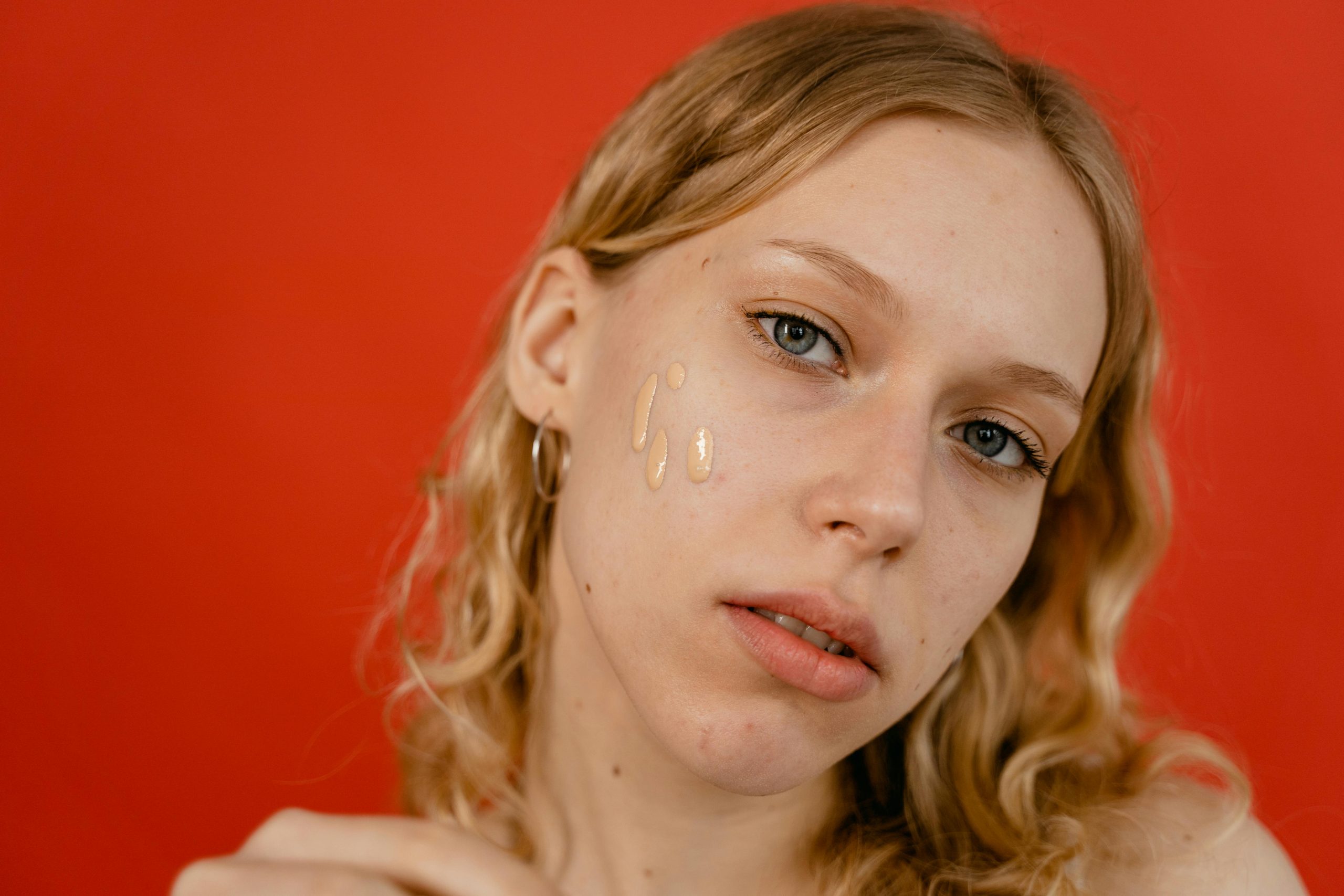 blonde woman with streaks of skin tint on her cheek